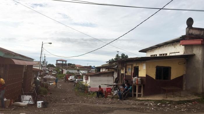 A wide shot of houses in a neighborhood of Malabo, Equatorial Guinea, with unpaved roads, one-storey houses, and trash 