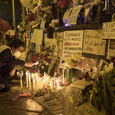 A woman lights a candle at a memorial for protesters who were injured or killed in Lima in November 2020, outside of Peru’s Congress building.