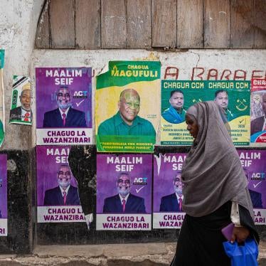 A woman walks past a wall with posters of presidential candidates in Zanzibar’s town on October 24, 2020