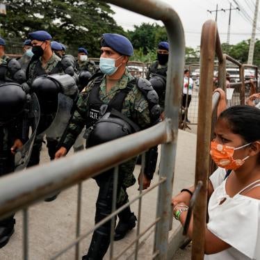 Soldiers walk carrying riot gear, while civilians look in behind barricades