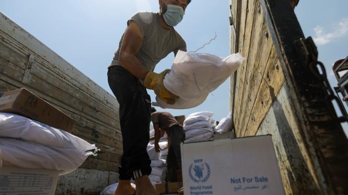 A worker unloads bags and boxes of humanitarian aid from the back of a truck in the opposition-held Idlib, Syria, June 9, 2021.