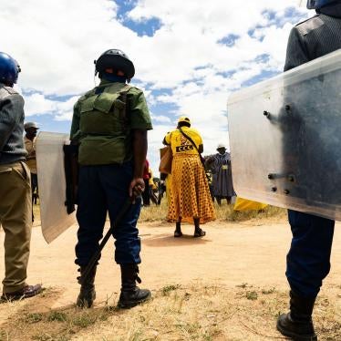 A line of police with riot shields stand in front of protestors