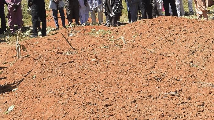 Community members stand at the grave side where victims of an army drone attack were buried in Tudun Biri village, Nigeria, December 5, 2023.