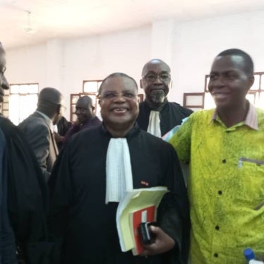 3 men stand smiling in a court room 