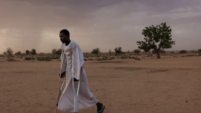 A man walks using crutches in a refugee camp