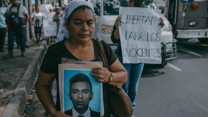 A woman holds a photo of her son at a protest