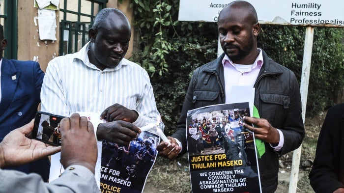 Activists light candles while holding posters at a tribute to the assassinated human rights lawyer Thulani Maseko, Eswatini, formerly Swaziland