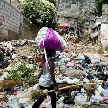 A woman carrying her belongings walks down a street in Port-au-Prince, Haiti. July 2024.