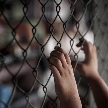  A young person holding onto a chain link fence.