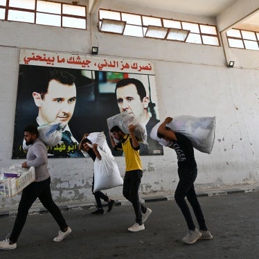 Displaced people walk past posters of President Bashar al-Assad as they enter Syria from Lebanon via the Jusiyeh Border crossing, on October 2, 2024. 