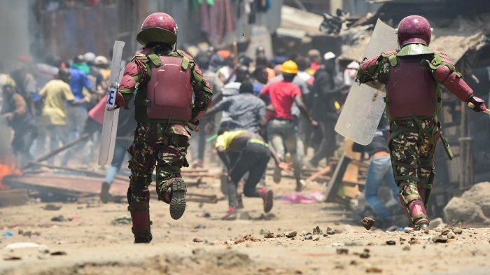 Armed riot police officers run towards protesters 