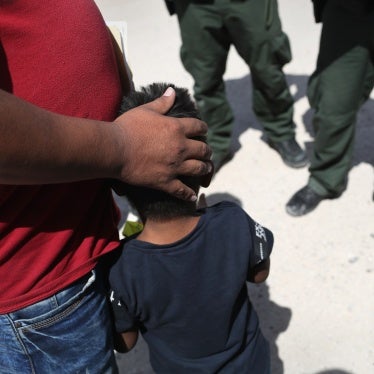 A father embraces his son in front of border agents