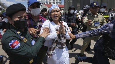 Environmental activist Phuon Keoraksmey is escorted by police officers