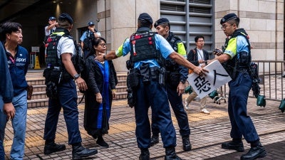 Police remove a sign from Elsa Wu, foster mother of activist Hendrick Lui