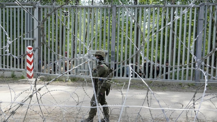 A Polish soldier patrols the metal barrier border with Belarus, in Bialowieza Forest, with migrants stranded on the Belarusian side, May 29, 2024.