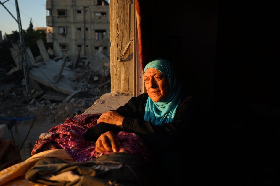 A woman looks out of the window of a damaged building