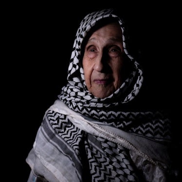 A photo of an older woman wearing a keffiyeh as a headscarf.