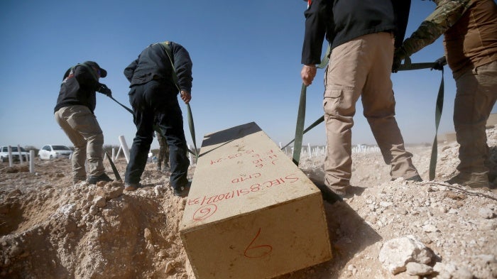 Officials from the forensic medical service place unidentified bodies in a mass grave