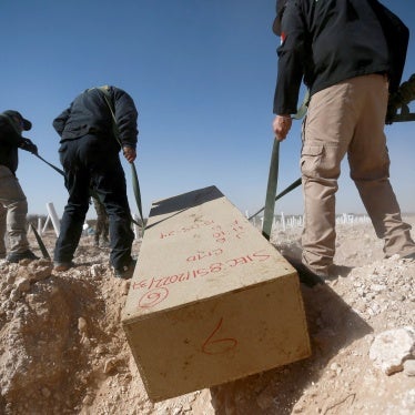 Officials from the forensic medical service place unidentified bodies in a mass grave