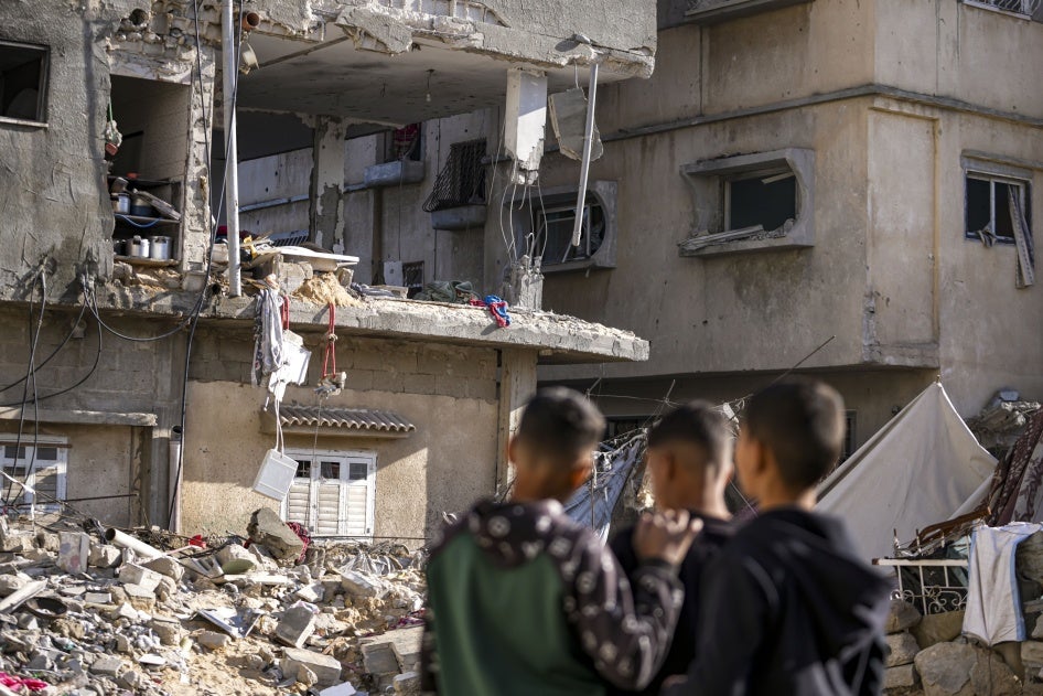 Three men look at a damaged building destroyed from an Israeli strike.