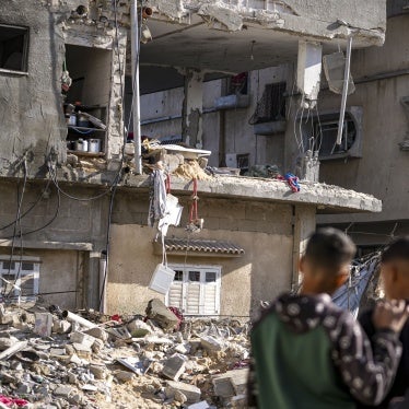 Three men look at a damaged building destroyed from an Israeli strike.