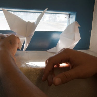 A youth holds two pieces of paper origami in a cell