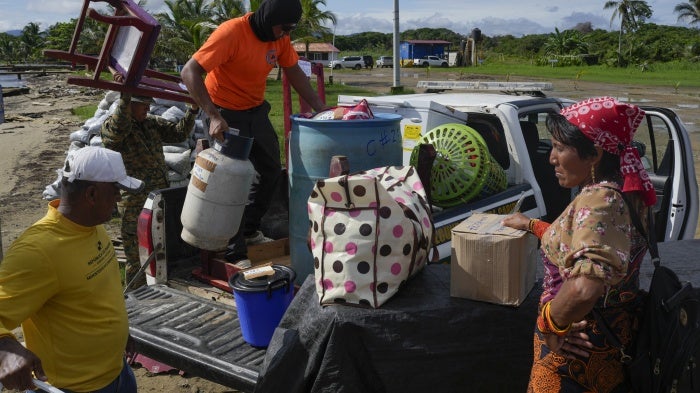 Civil protection officials, left, load a family's belongings on a truck to move from the island of Gardi Sugdub, located off Panama's Caribbean coast, to Nuevo Carti on the mainland, June 5, 2024.